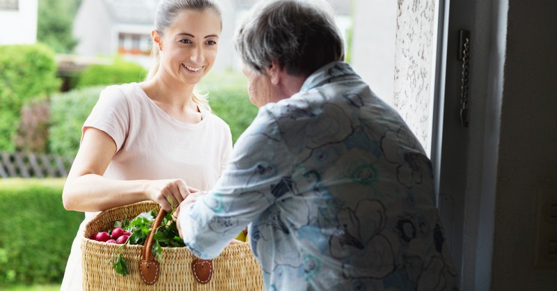 woman giving food to older woman