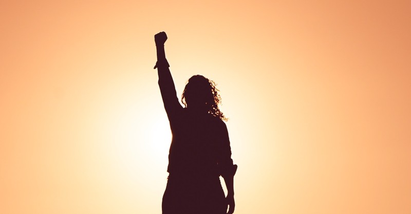 woman with fist pump of victory in air at sunset