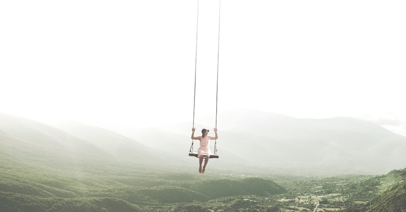 Woman hanging on swing over a valley
