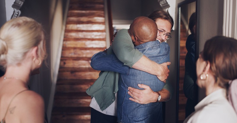 Two friends hugging in welcome, at a front door