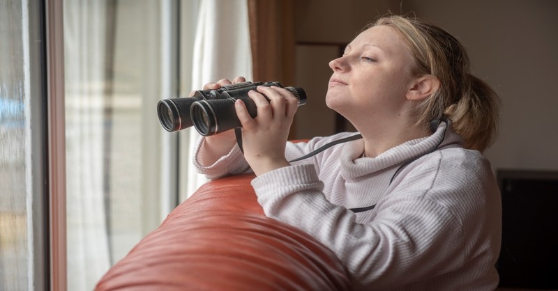 woman looking out window with binoculars, love my neighbor