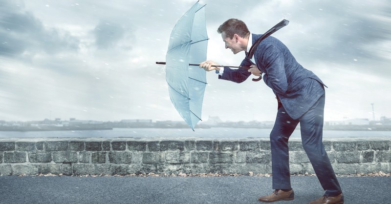 Businessman struggling with an umbrella in a storm