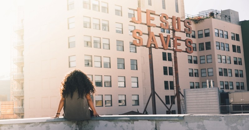 woman sitting on building ledge looking at jesus saves sign, honor your father