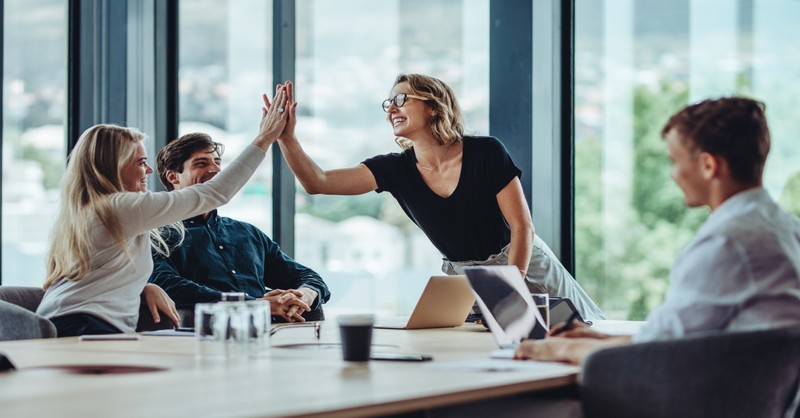 Female professional giving a high five to her colleague in conference room, overcome evil with good