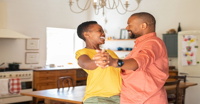 Young African-American couple dancing and laughing in kitchen, leave and cleave