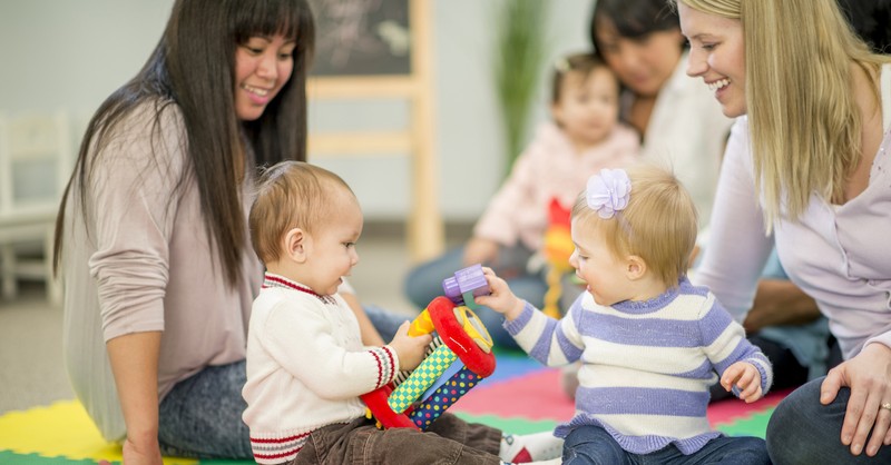 moms talking at preschool event with kids playing in front