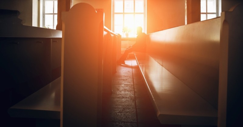 Man in church pew with sunlight obscuring face, speaking in tongues