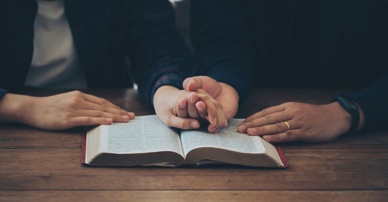 Couple praying together over Bible