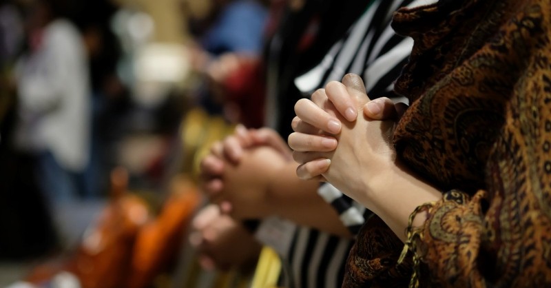 Close-up of a group of people with hands folded in prayer