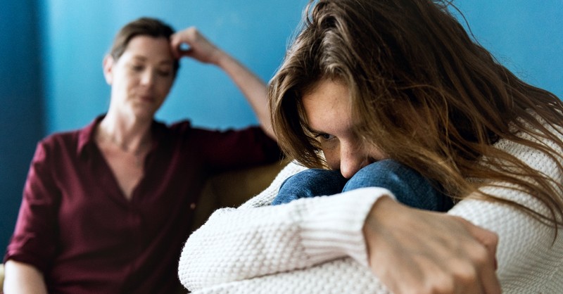 Woman crying while another looks on hurt