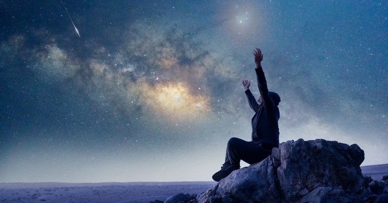 Man raising his hands to a starry sky