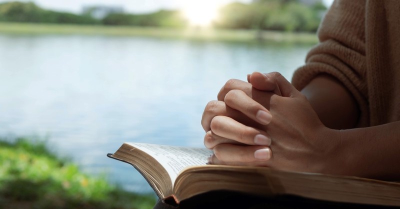 woman reading bible by river