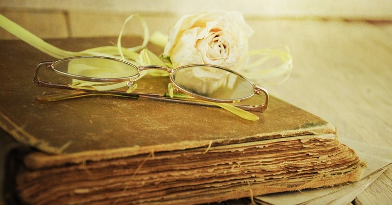 romance hardcover book with glasses and white rose on top