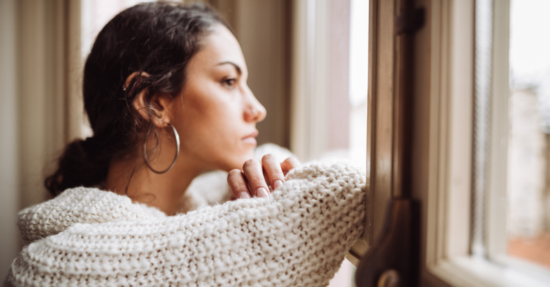 Woman waiting patiently, leaning on her arms and looking out a window.