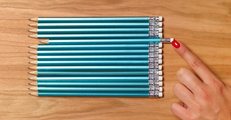 Woman carefully arranging pencils so they are all even, perfectionist