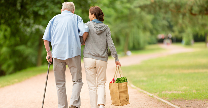 Woman helping elderly man with groceries; 7 lessons my dad taught me about living generously.
