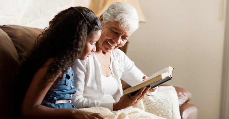 Senior grandparent reading Bible to grandchild
