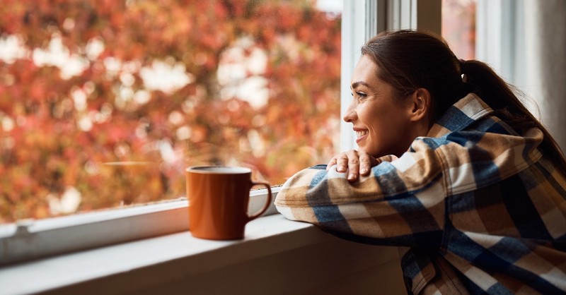 Woman looking out at fall leaves