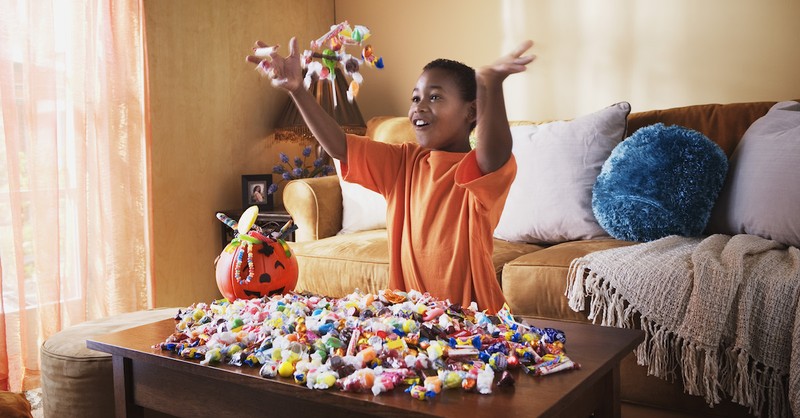 little kid enjoying halloween candy in living room after trick or treating