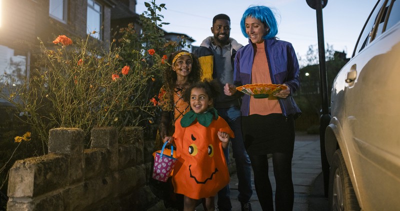 family trick or treating together in neighborhood