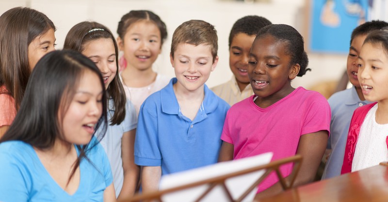 kids singing around piano singing hymns
