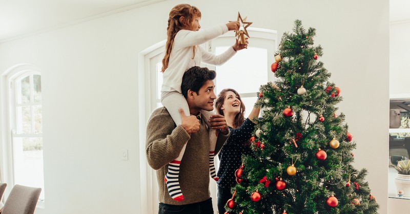 Happy family at christmas girl putting star on christmas tree