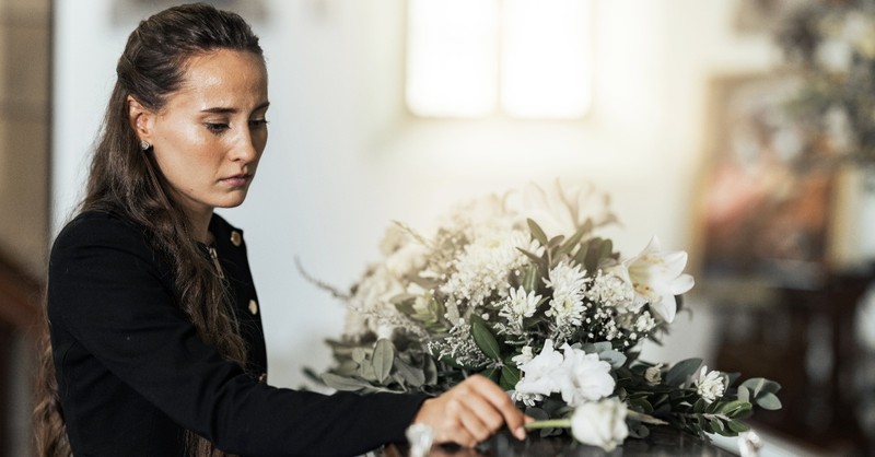 Woman placing a flower on a coffin