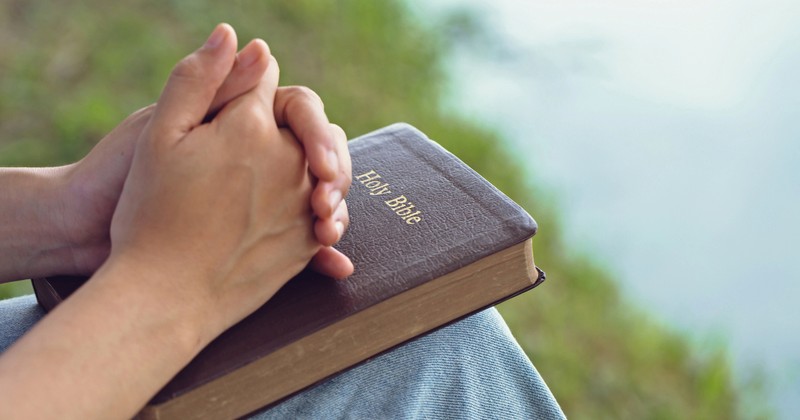 Hands in Prayer on Bible, speaking in tongues