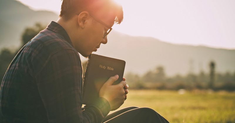 Man praying with Holy Bible outside