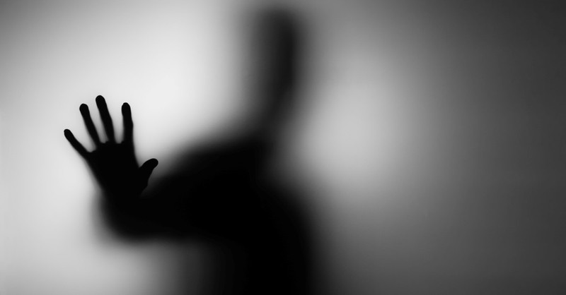 Fuzzy, scary silhouette of a man reaching out a hand