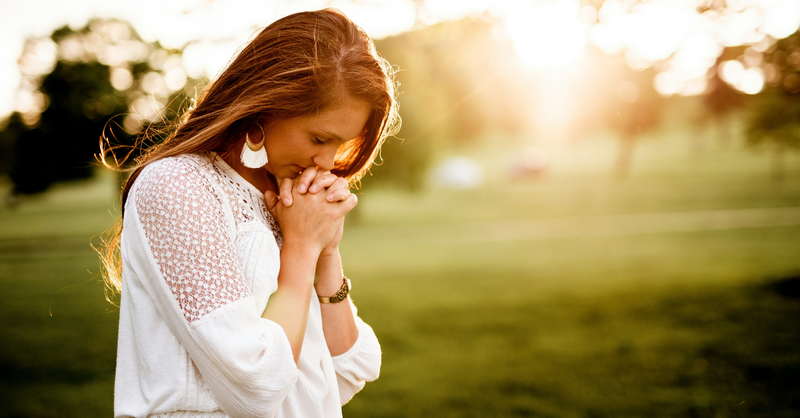 Young woman praying outside at sunrise