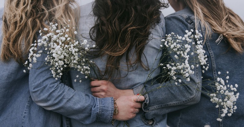 women friends holding eachother's backs while holding baby's breath