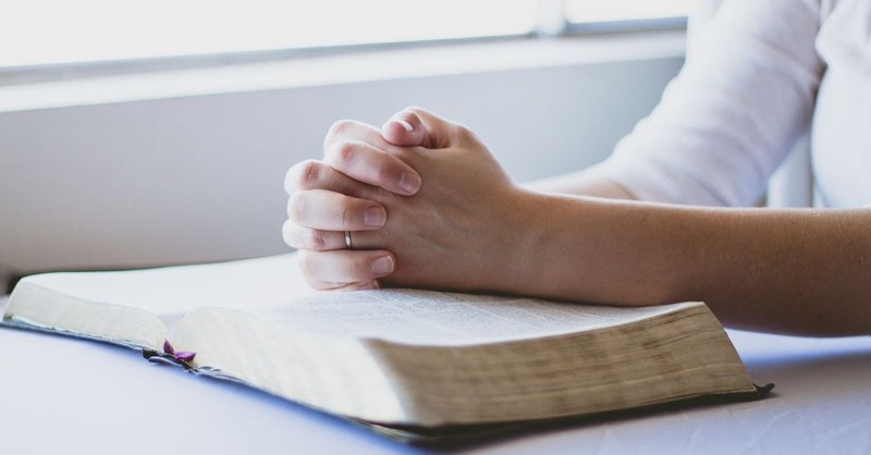 Woman praying over an open Bible.