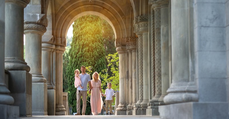 family standing together under columns area of building that looks like a church