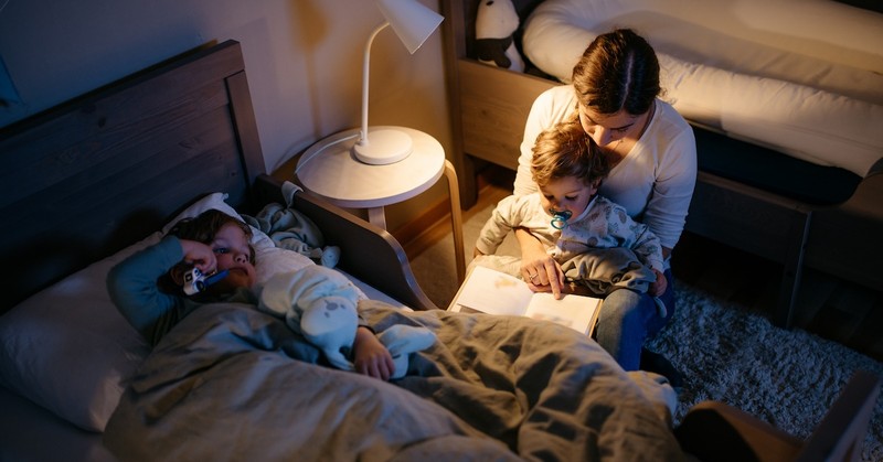 Mom reading book to kids in bed nighttime bedtime sleep
