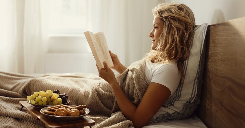 Woman happy breakfast in bed reading book relaxing