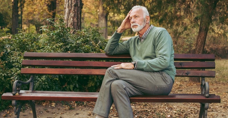 Senior man waiting on bench thinking