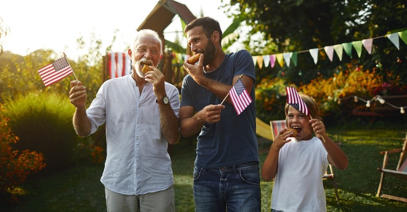 Grandpa and son and grandson fourth of july picnic outside american flag