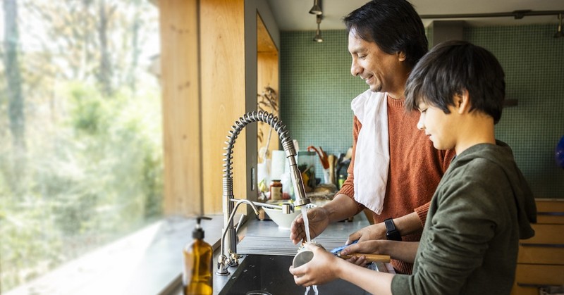 Dad and son washing dishes chores in kitchen