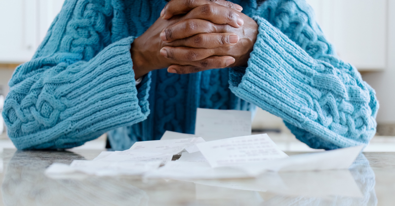 hands praying Bible table bills finances