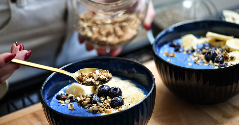 A glass jar or bowl of overnight oats with fresh berries, nuts, and a spoon.
