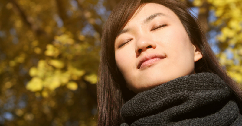 women breathing deeply with eyes closed in nature