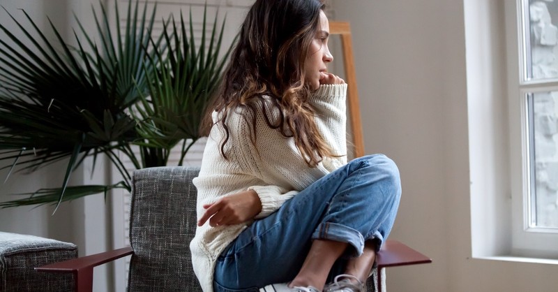woman looking worried sitting by window
