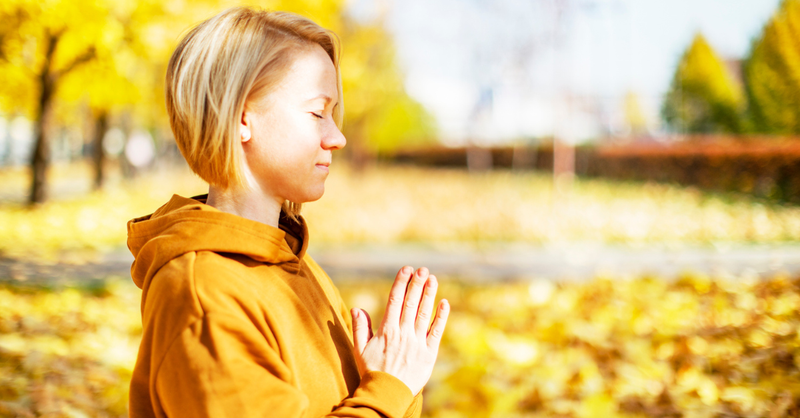 woman praying in autumn park