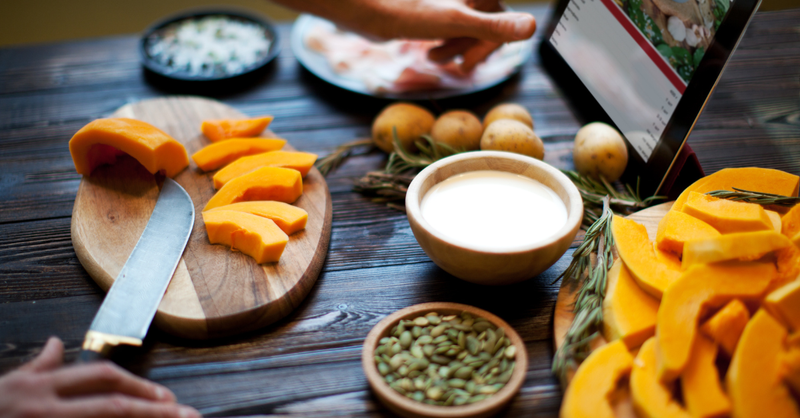 Cutting Butternut Pumpkin and reviewing recipe on mobile in kitchen