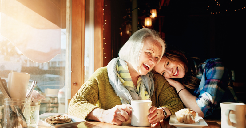Mother and daughter laughing together at coffee shop