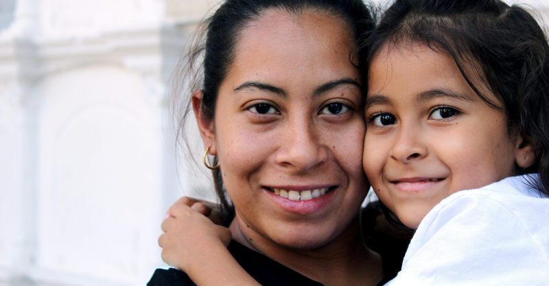 A smiling mother and young daughter embrace while looking at the camera, representing a mother's love, God's protection, and trusting Him with the safety, future, and well-being of children.