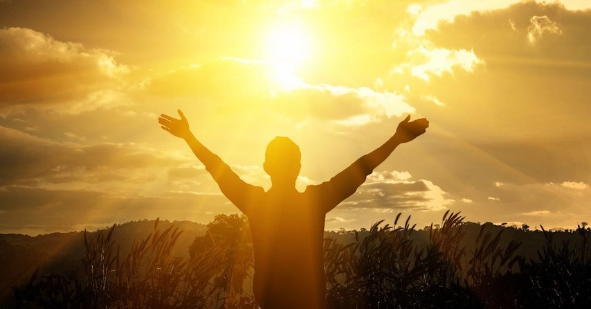 Man holding hands up to the sun