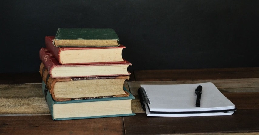 Five books stacked on table next to notebook with paper, prayer trusting god in hard seasons