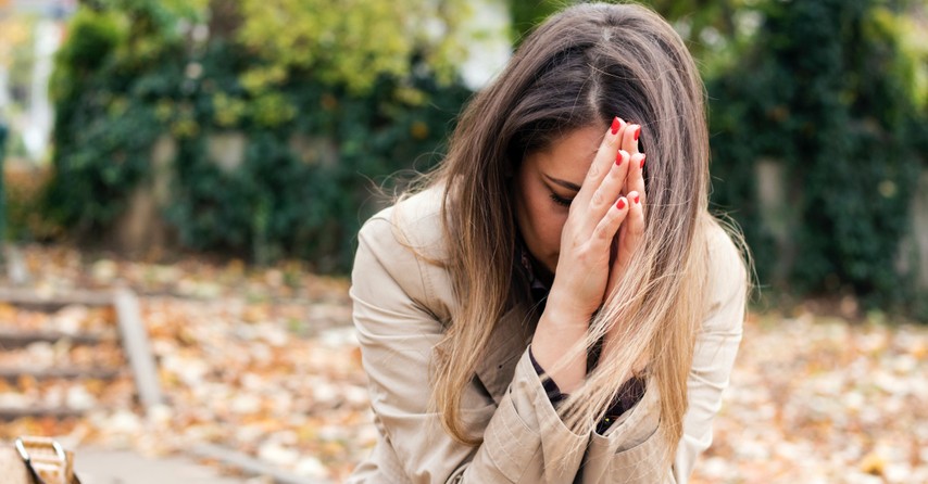 Woman outside with hands raised in prayer